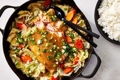 a skillet filled with rice, meat and vegetables next to a bowl of rice