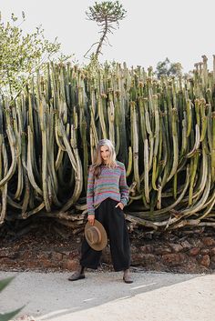 a woman standing in front of a large cactus