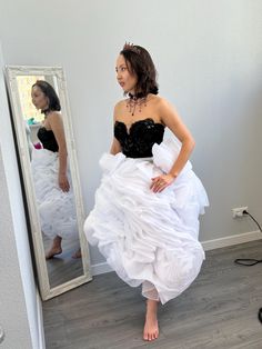 a woman is standing in front of a mirror wearing a white dress with ruffles