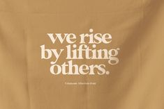 a brown shirt with white lettering that says, we rise by lifting others up to the ceiling