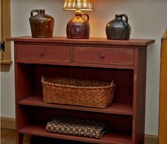 a wooden shelf with two vases and a basket on it next to a lamp