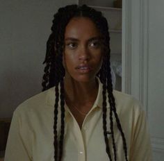 a woman with long dreadlocks standing in front of a door and looking at the camera