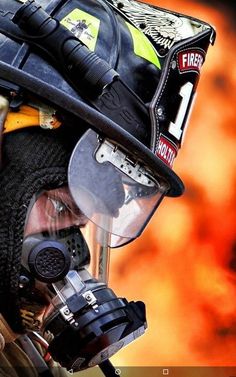 a man wearing a firefighter's helmet and goggles with flames in the background