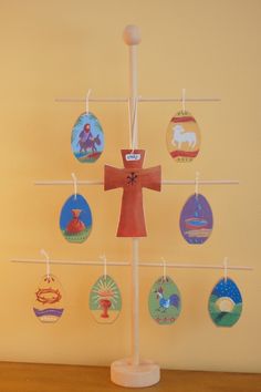 a cross on top of a wooden table with ornaments hanging from it's sides