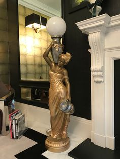 a gold statue holding a lamp on top of a black and white checkered floor