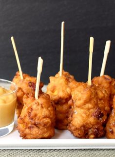 small appetizers with toothpicks are on a white plate