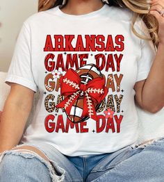 This Arkansas Game Day Tee Shirt is perfect for women looking to show their team spirit with a cute bow and football design. It provides a casual and comfortable vibe, making it ideal for game days, tailgates, and sports events. The lightweight fabric and retail fit make it easy to layer and style for various occasions. Product features - Made with 100% Airlume combed and ring-spun cotton for breathability - Retail fit perfect for casual and semi-formal settings - Tear-away label for minimal ski Arkansas Game Day, Football Design, Womens Football, Ladies Tee Shirts, Cute Bows, Jersey Tee, Football Fans, Sport Event, Short Sleeve Top