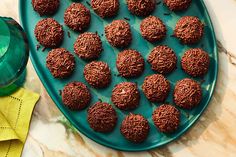 chocolate truffles are arranged on a blue platter next to a green bottle