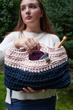 a woman holding a crocheted purse in her hands