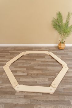 a potted plant sitting on top of a hard wood floor next to a wooden hexagonal frame