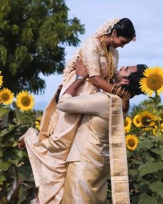 a bride and groom kissing in front of sunflowers