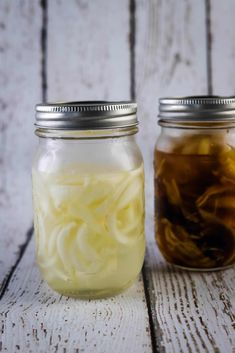 two jars filled with food sitting on top of a wooden table next to each other