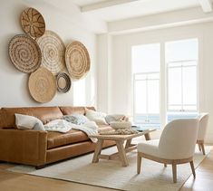 a living room filled with furniture next to a large window covered in wicker baskets