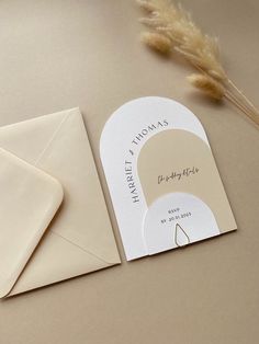 a close up of an envelope on a table with a card and some flowers next to it