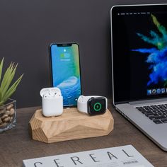 an open laptop computer sitting on top of a wooden desk next to two airpods