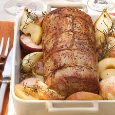 a meatloaf with apples and rosemary garnish in a white casserole dish