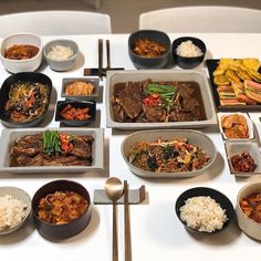 a table topped with lots of different types of food and bowls filled with meats