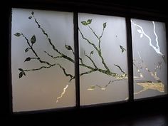 three windows with leaves on them in a dark room