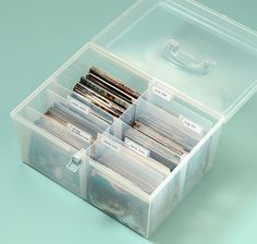 a plastic container filled with lots of different types of files and folders on top of a blue surface