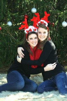 two women hugging each other in front of a christmas tree with red and white decorations