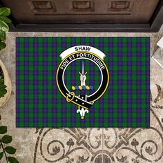 a door mat with the clan crest and tartane on it, in front of a potted plant