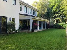 a large white house sitting on top of a lush green field next to a swimming pool