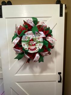 a red and green christmas wreath hanging on a white door with the words peppermint candy written on it