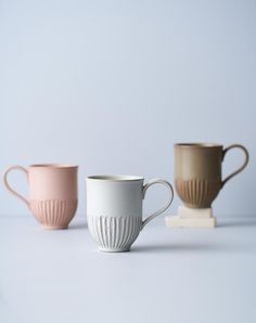 three coffee mugs sitting next to each other on top of a white countertop