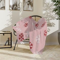 a chair covered in a pink blanket with snowflakes on it next to a potted plant