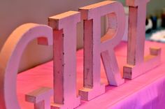 wooden letters that spell out the word bride on a pink table cloth covered tablecloth