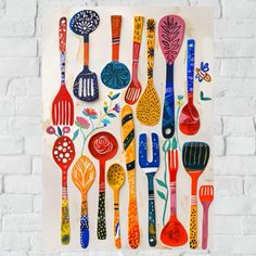 colorful spoons and spatulas are arranged on a white brick wall