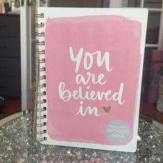 a pink notebook with the words you are beloved in it on a glass top table