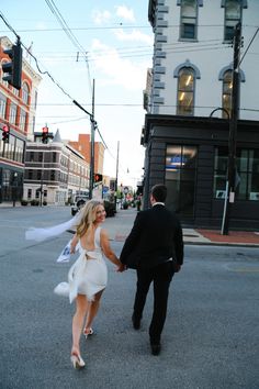 a man and woman are walking down the street holding each other's hands as they walk