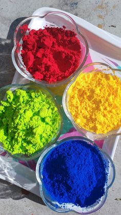 three bowls filled with different colored powders on a tray next to another bowl full of them