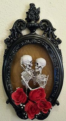 two skeletons in a frame with red roses