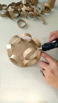 a person is cutting out some cardboard circles with scissors and glue on a white table