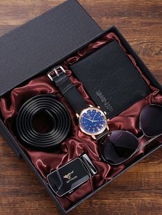 a watch, sunglasses, tie and wallet in a black box on a wooden table