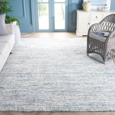 a living room area with blue walls and white furniture, including a large rug on the floor