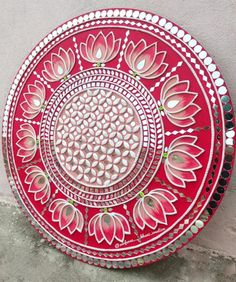 a red and white plate sitting on top of a cement floor next to a wall