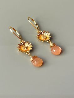 "Sunflower earrings. Lovely facetted peach moonstone teardrops wrapped in 14k gold fill hang from gold dipped sunflowers on 14k gold fill lever backs. Total Earring length: 42mm (approx 1 5/8\") Drop length: 22mm (approx 1 1/8\") Photos are zoomed to show detail - please note measurements and see photo on model for scale. I lovingly handcraft all jewelry and hair accessories one at a time in my northern Michigan studio. Gemstones are naturally formed so please expect some slight variations in co Peach Jewelry, Blue Opal Necklace, Emerald Earrings Studs, Sunflower Earrings, Peach Moonstone, Northern Michigan, Moonstone Jewelry, Dangly Earrings, Flower Jewelry