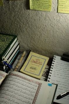 there are many books on the table with pens and paper attached to it, including arabic writing