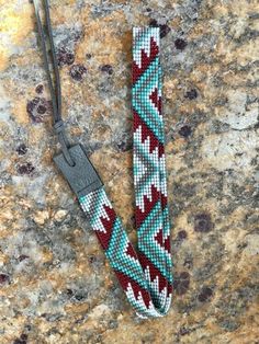 a lanyard on a granite surface with a metal hook in the middle that has a red, white and blue bead design