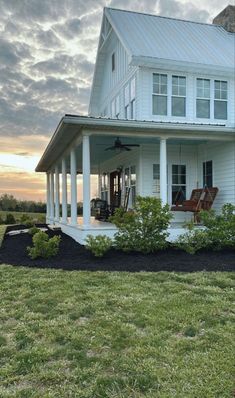 a large white house sitting on top of a lush green field under a cloudy sky