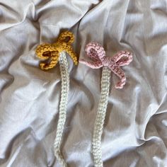 two crocheted bows are laying next to each other on a white bed sheet