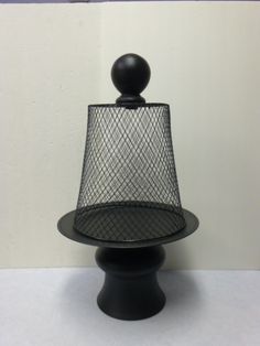 a black table lamp with a mesh shade on it's base and a white wall in the background