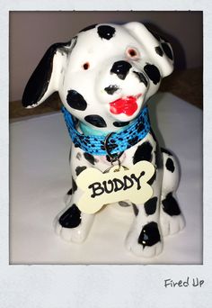 a ceramic dog figurine with a bone in it's mouth and the word buddy on its collar