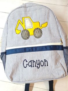 a blue and white striped backpack with a yellow construction truck on it