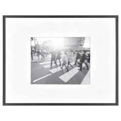 black and white photograph of people walking across a crosswalk with the sun behind them