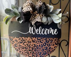 a welcome sign is hanging on the front door with leopard print and black ribbon around it