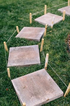 several cement blocks are placed in the grass with clothes pins attached to them, and one block is missing